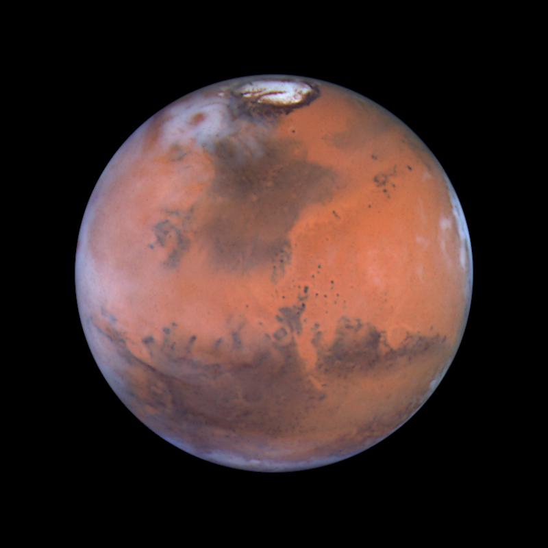 A full-disc view of Mars from the Hubble Space Telescope, showing its rusty surface, dark markings and a bright polar cap
