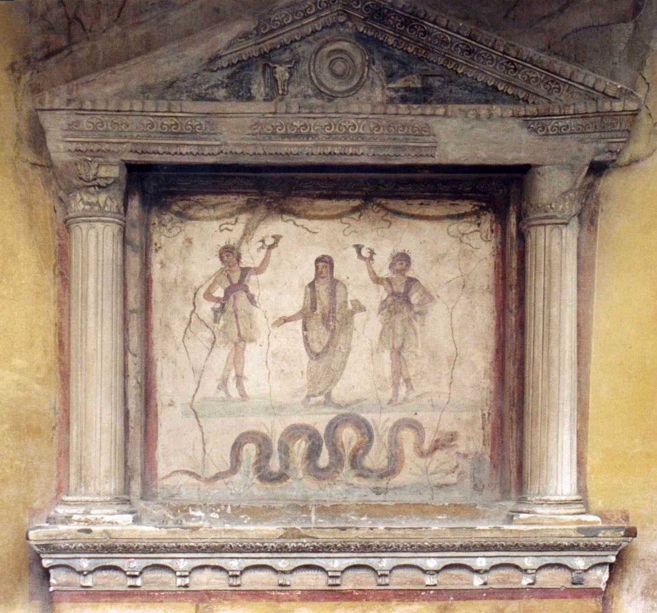 Roman household shrine with the genius between two dancing Lares and a serpent below